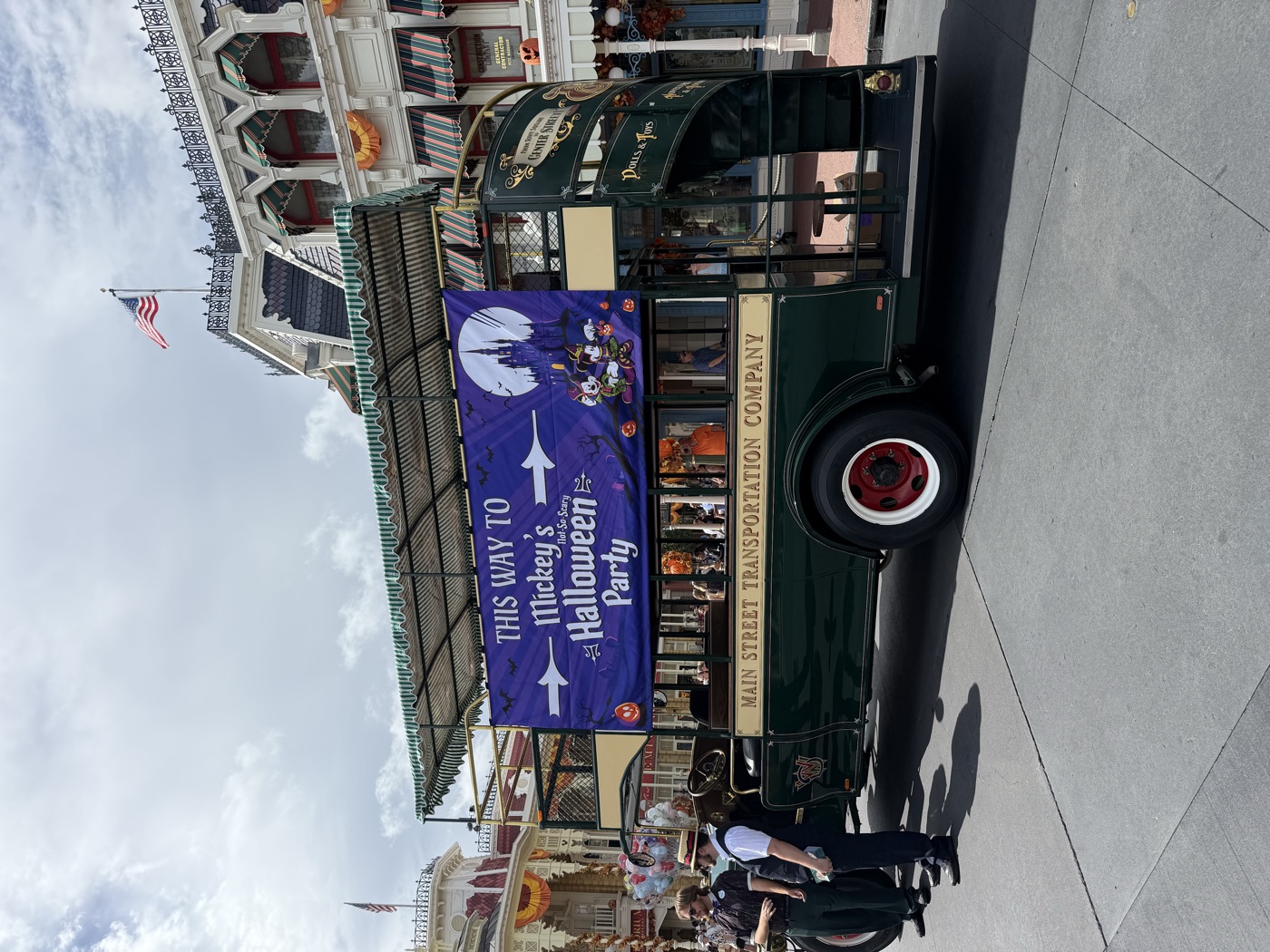 The Main Street trolley wearing its 'This Way to Mickey's Not-So-Scary Halloween Party' banner in the afternoon sun